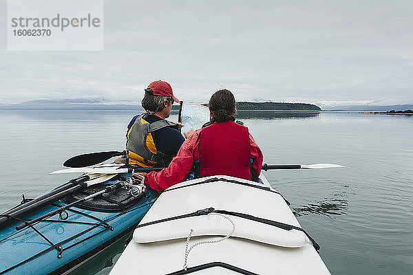 Seekajakfahrer beim Blick auf die Seekarte und die japanische Bucht an der Küste Alaskas.