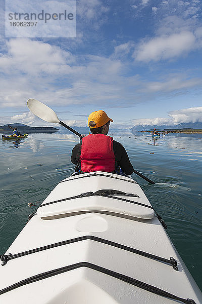 Eine kleine Gruppe von Menschen paddelt in den unberührten Gewässern einer Bucht an der Küste Alaskas.