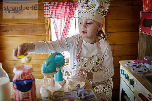 Junges Mädchen im Wendy-Haus  das vorgibt  in der Küche zu kochen