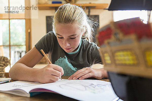 12-jähriges Mädchen zeichnet zu Hause im Skizzenblock