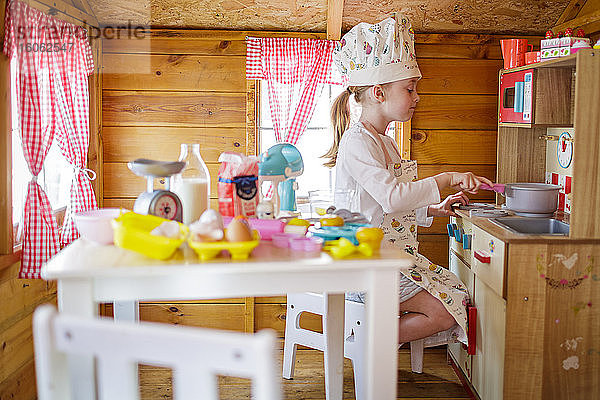 Junges Mädchen im Wendy-Haus  das vorgibt  in der Küche zu kochen