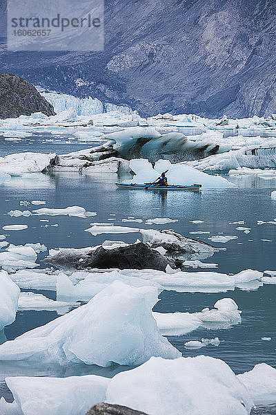 Ein Seekajak  der durch Eis in der Lagune am Ende des McBride Glacier paddelt.