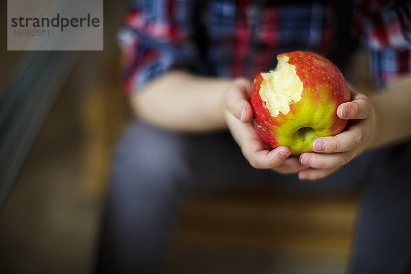 Nahaufnahme der Hände eines Kleinkindes  das einen teilweise gegessenen Apfel hält