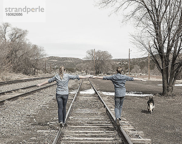 Vor-Teenager-Freundinnen  die zusammen auf Eisenbahnschienen gehen NM.
