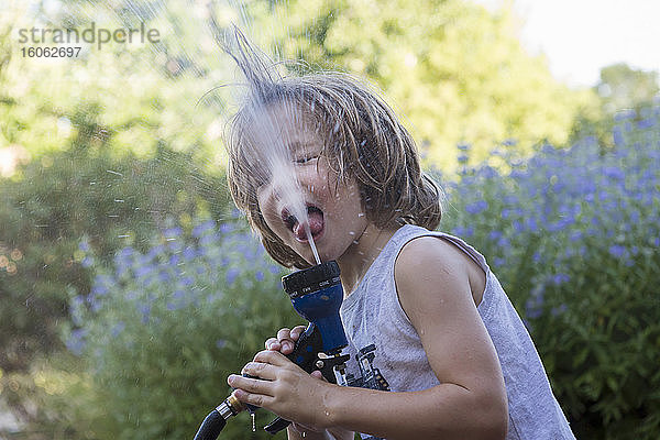 5 Jahre alter Junge trinkt aus Wasserschlauch