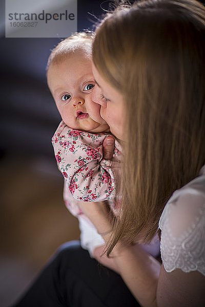 Frau küsst ein junges Baby auf die Wange