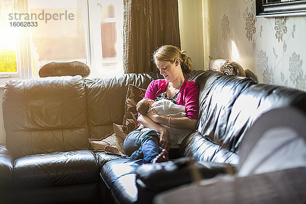 Mutter entspannt sich mit schlafendem Baby auf dem Sofa