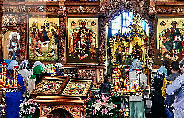 Astrachan  Russland. Die Mariä-Entschlafens-Kathedrale befindet sich im Kreml von Astrachan. Die Menge der Gläubigen versammelt sich vor der mit Ikonen bedeckten Ikonostase. Die Ikonostase gilt als Tor zur göttlichen Welt.