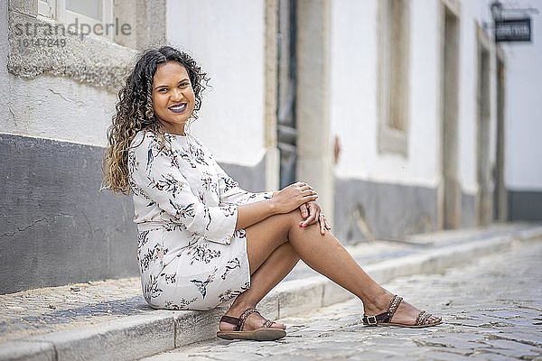 Schöne Frau sitzt auf dem Bürgersteig einer portugiesischen Straße  Portugal  Europa