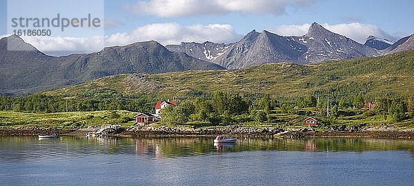 Wohnhaus mit Boot am Fjord  hinten Berggipfel  Insel Senja  Botnhamn  Troms  Norwegen  Europa