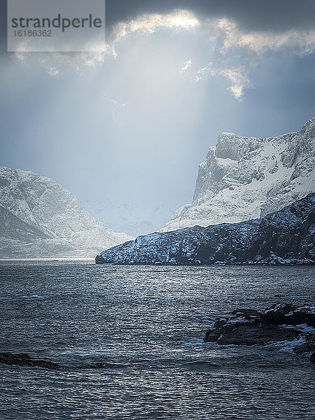 Dramatische Lichtstimmung in den Wolken über dem winterlichen Meer  Berge  Vesteralen  Hovden  Nordland  Norwegen  Europa