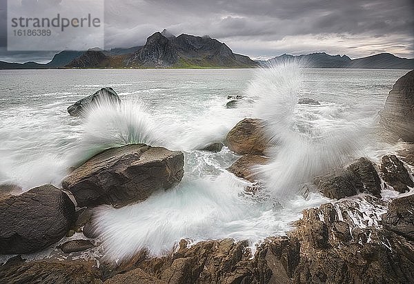 Spritzende Wellen auf Felsküste  hintern Lofotenberge  Lofoten  Nordland