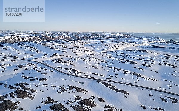Einsame Straße zum Nordkap in schneebedeckter arktischer Landschaft mit Auto  Finnmark  Norwegen  Europa