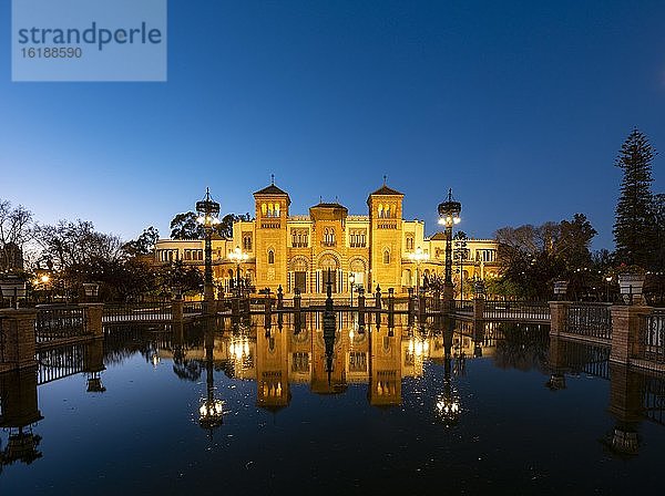 Beleuchtetes Kunstmuseum Museo de Artes y Costumbres Populares de Sevilla spiegelt sich in einem Brunnen  blaue Stunde  Plaza de America  Sevilla  Andalusien  Spanien  Europa