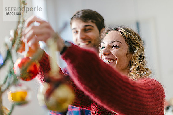 Paar schmückt den Weihnachtsbaum zu Hause