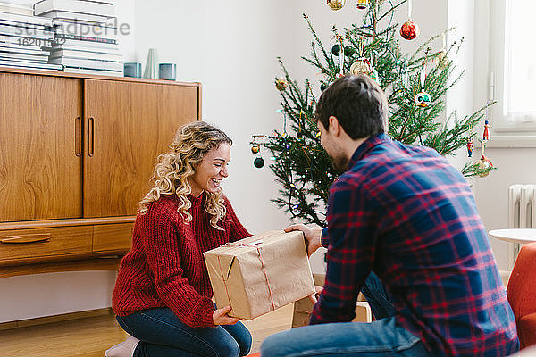 Ehepaar legt zu Hause Geschenke unter den Weihnachtsbaum