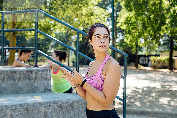 Frau benutzt Handy im Park  Freunde machen im Hintergrund Pause