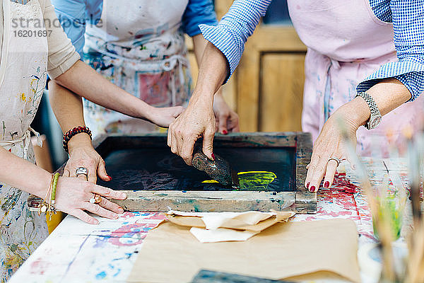 Drei Frauen arbeiten im kreativen Atelier am Siebdruck