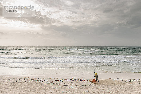 Einheimischer Mann harkt Sand am Strand  Tulum  Mexiko