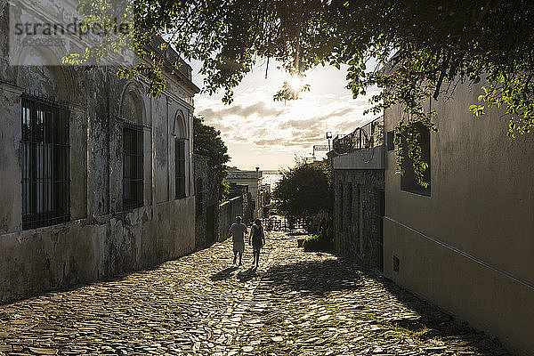 Zwei Menschen schlendern die gepflasterte Straße entlang  Barrio Historico (Altstadt)  Colonia del Sacramento  Colonia  Uruguay