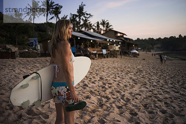 Frau mit Surfbrett in der Hand  Blick aufs Meer  Balangan  Bali  Indonesien