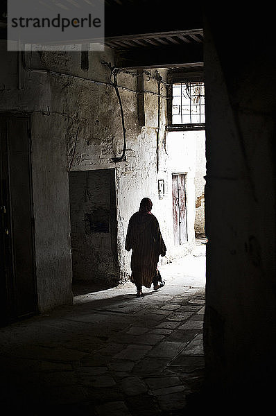 Silhouette einer Frau  die durch eine Gasse geht  Medina von Fes  Marokko