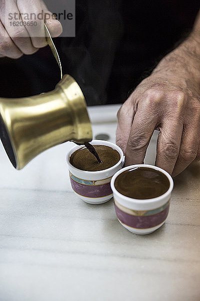 Ältere männliche Hände gießen traditionellen marokkanischen Kaffee ein