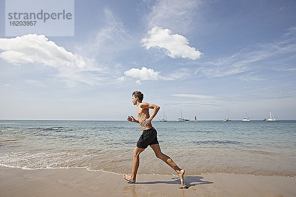 Junger Mann läuft am Meeresufer entlang  Koh Lipe  Thailand