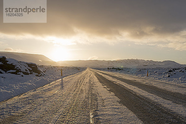 Sonnenbeschienene vereiste Landstraße im Winter  Reykjanes  Südisland