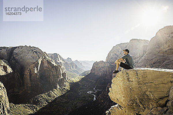 Mann wandert auf dem Angels Landing Trail  sitzt auf einem Felsen  Zion National Park  Utah  USA