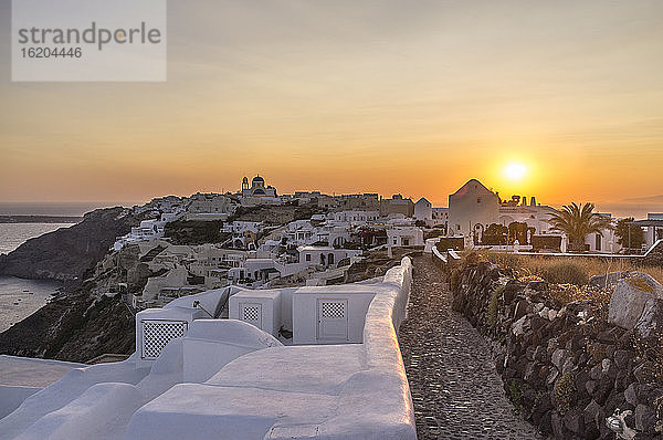 Blick auf weiß getünchte Mauern und die Stadt bei Sonnenuntergang  Oia  Santorin  Griechenland