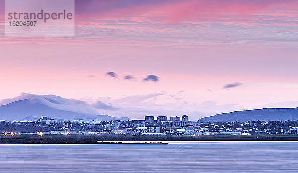 Blick über das Wasser auf die Skyline von Reykjavik um Mitternacht  Island