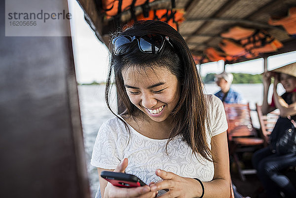Frau betrachtet Foto auf Mobiltelefon auf Kreuzfahrtschiff  Mekong-Delta  Vietnam