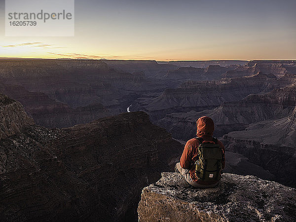 Mann sitzt am Rande des South Rim  Grand Canyon National Park und schaut auf den Sonnenuntergang  Arizona  USA