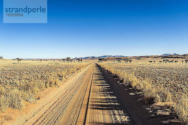 Schotterstraße in flacher Landschaft im Namibrand-Naturreservat  Namibia
