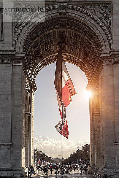 Ansicht der französischen Flagge und des Arc de Triomphe im Sonnenlicht  Paris  Frankreich