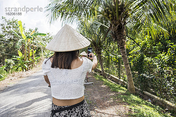 Frau mit traditionellem Reishut  die ein Selfie macht  Insel Tan Phong  Vietnam