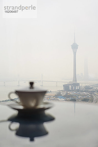 Teetasse auf dem Tisch mit nebligem Blick auf den Fluss und den Macau Tower  Macau