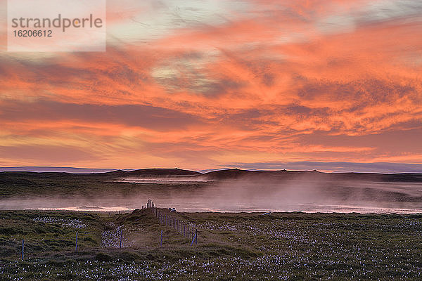 Wolkenbedeckte Vulkanlandschaft unter orangefarbenem  dramatischem Himmel  Island