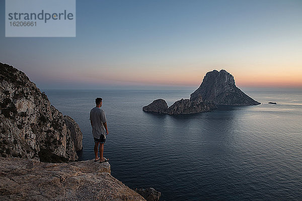 Junger Mann beobachtet Sonnenuntergang über Es Vedra  Ibiza  Spanien