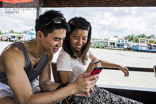 Ein Paar betrachtet ein Handyfoto auf einem Kreuzfahrtschiff  Mekong-Delta  Vietnam