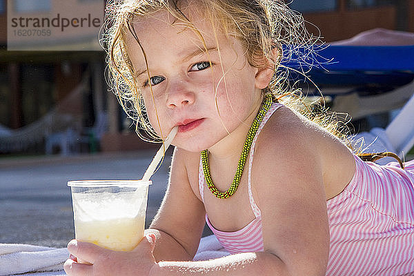 Porträt eines 3 Jahre alten Mädchens  das an einem Getränk nippt