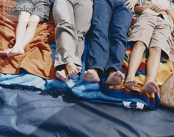 Vierköpfige Familie auf Schlafsäcken in einem Zelt liegend  Hüfte unten