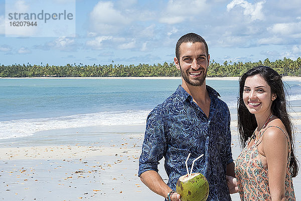 Ein gutaussehendes hispanisches (lateinisches) Paar lächelt und steht zusammen an einem einsamen Strand  Brasilien  Südamerika