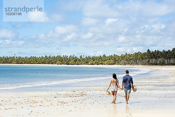 Ein gut aussehendes hispanisches (lateinamerikanisches) Paar beim Spaziergang an einem einsamen Strand mit dem Rücken zur Kamera  Brasilien  Südamerika