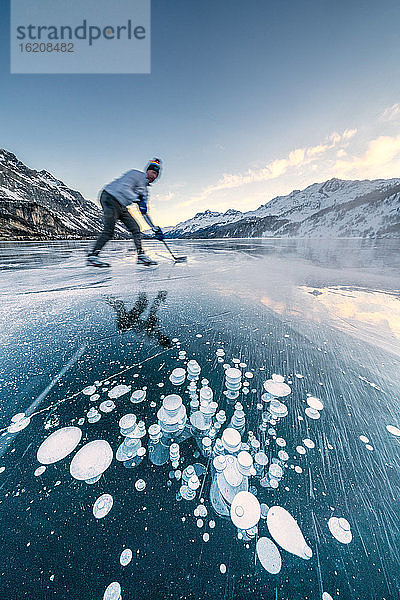 Mann spielt Eishockey auf dem zugefrorenen Silsersee  Engadin  Kanton Graubünden  Schweiz  Europa