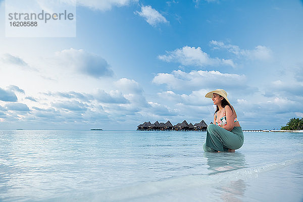 Eine indische Touristin am blauen Wasser und weißen Sandstrand  Die Malediven  Indischer Ozean  Asien