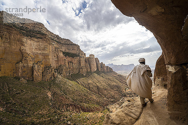 Rückansicht eines Priesters  der auf dem Zugangsweg zur in den Fels gehauenen Abuna-Yemata-Guh-Kirche geht  Gheralta-Gebirge  Region Tigray  Äthiopien  Afrika