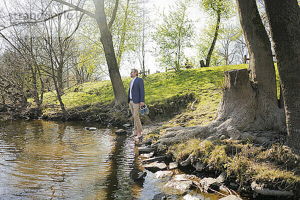 Männlicher Unternehmer steht am Flussufer im Park