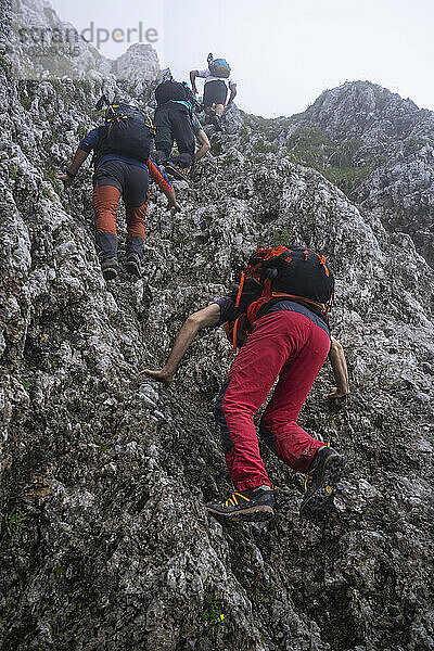 Männliche Wanderer mit Rucksäcken beim Klettern auf einem Berg  Bergamasker Alpen  Italien